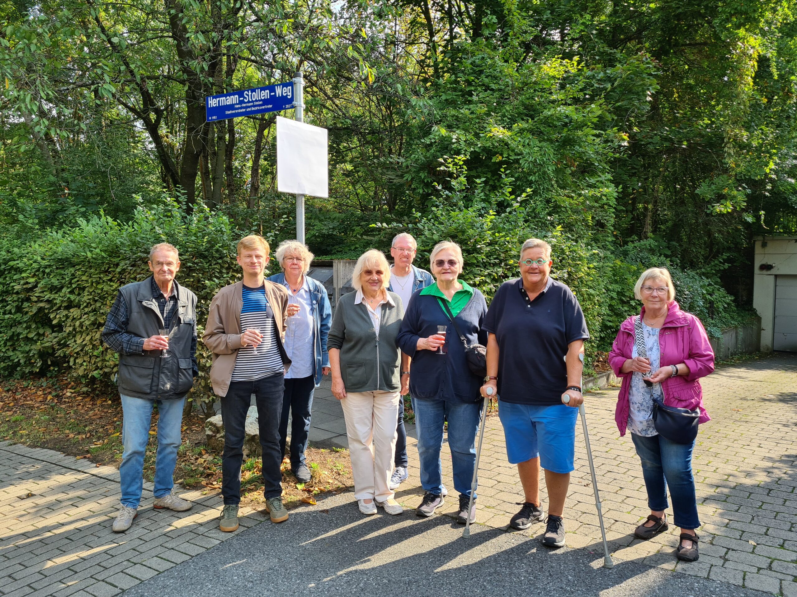 Grüne Partei- und Frakionsmitglieder unter dem Schild Hermann-Stollen-Weg stehend